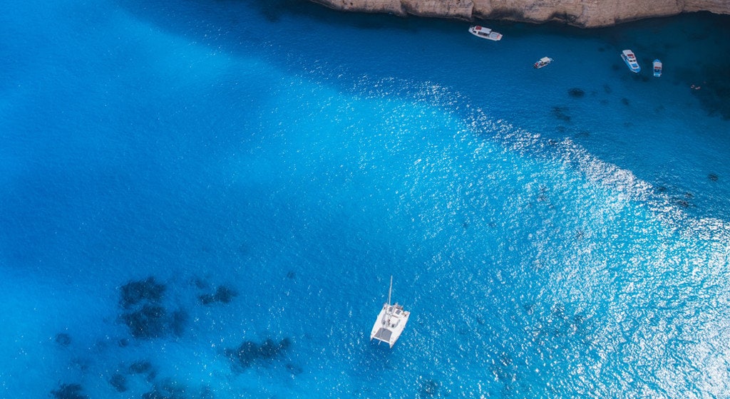five yachts float on surface of crystle clear and blue sea water